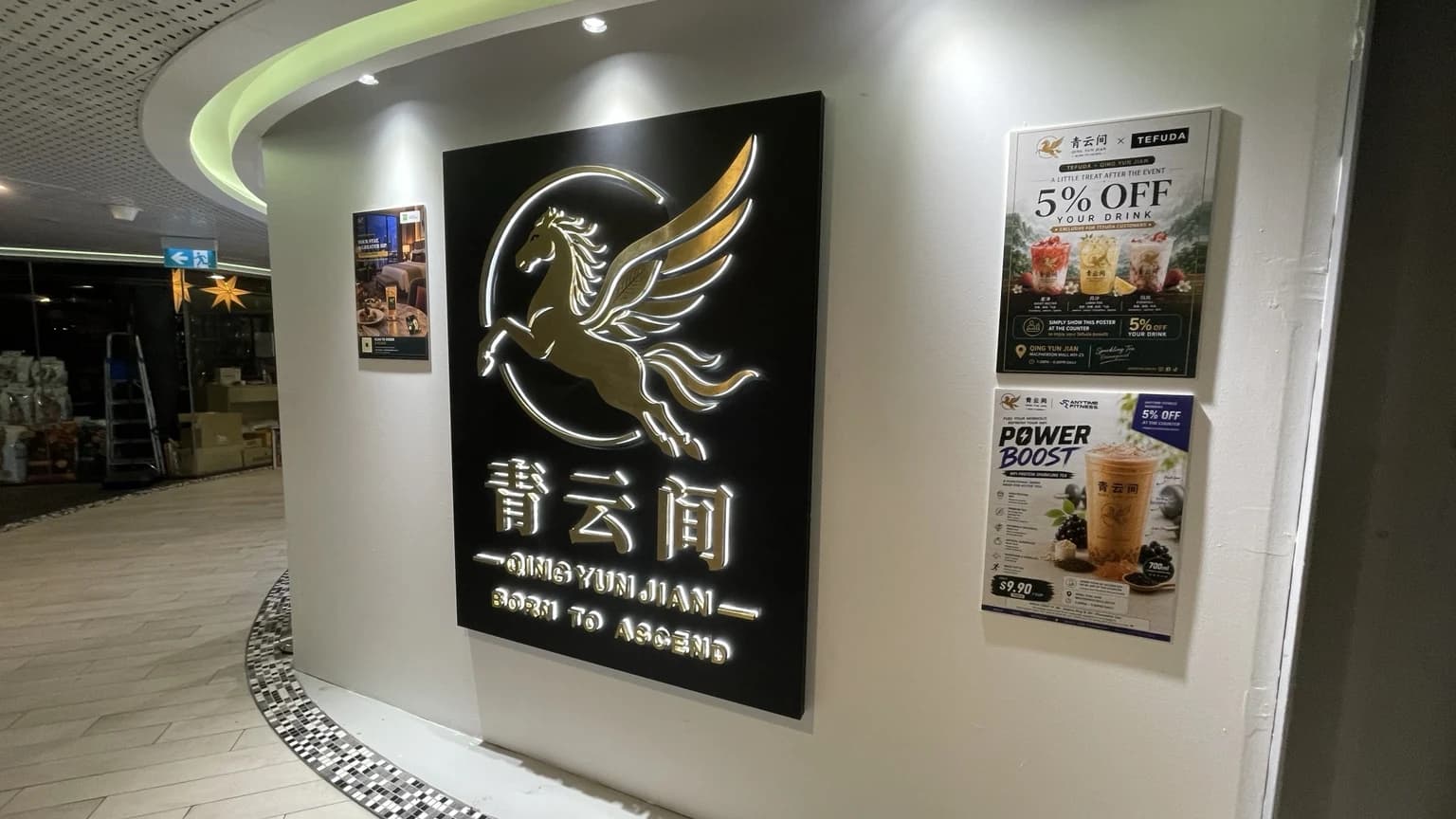 The illuminated gold Pegasus and Born to Ascend lettering on the Qing Yun Jian wall sign